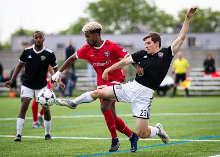 MISSISSAUGA, ON – JUN. 14, 2019: Michael Thornton of Durham United FA and Jordan Prescod of North Mississauga SC battle for the ball during a League1 Ontario regular season game. MISSISSAUGA, ON - JUN. 14, 2019: Michael Thornton of Durham United FA and Jordan Prescod of North Mississauga SC battle for the ball during a League1 Ontario regular season game.
